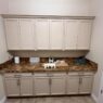 Cabinet refinishing project in Houston utility room showing cream-colored cabinets with metallic handles, stone countertop in earthy tones, organized decor, and neutral walls.