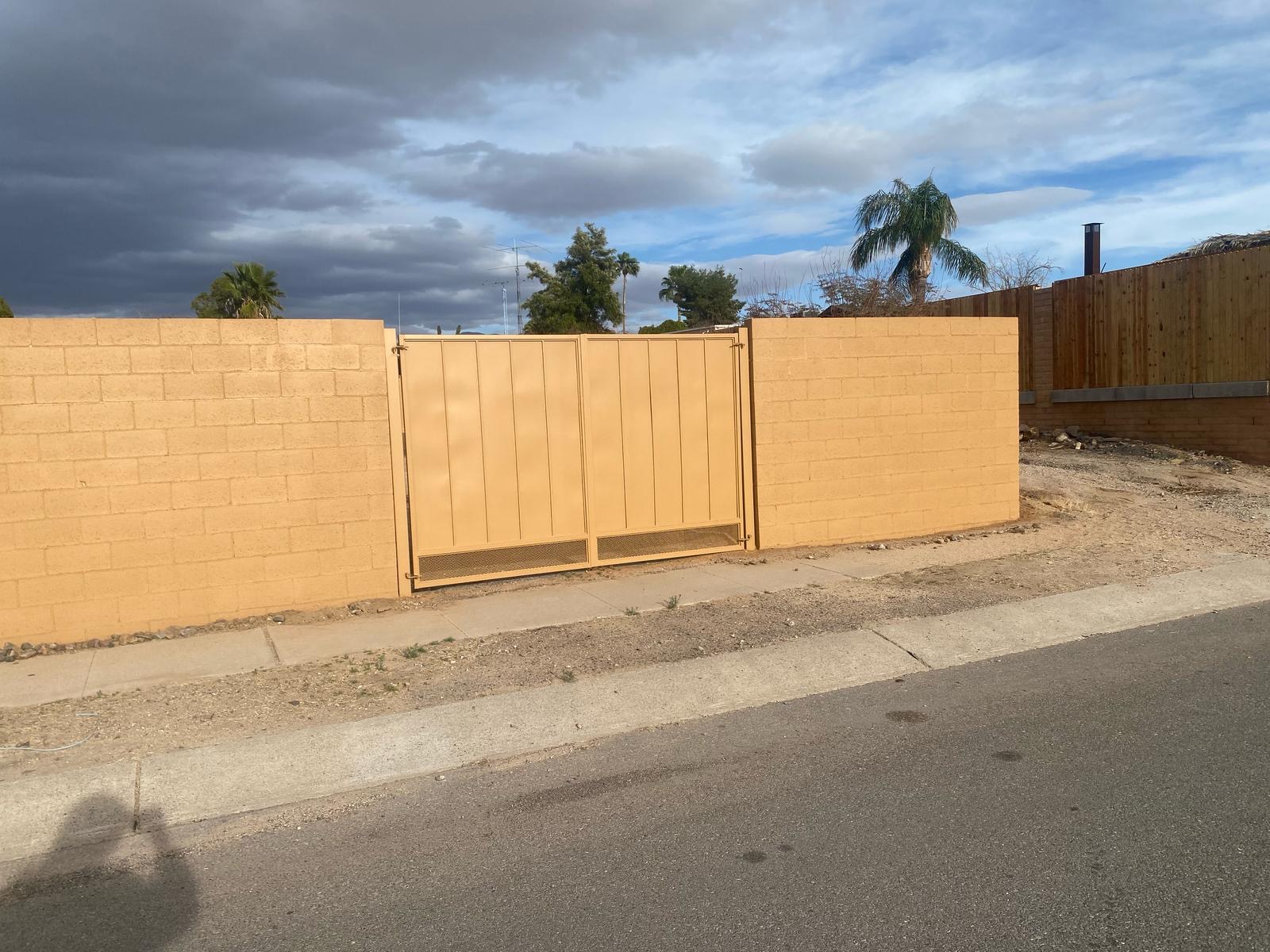 Gate and Fence Painting in Tucson with earthy tones blending into the desert landscape under a dramatic sky, showcasing quality craftsmanship and regional harmony.