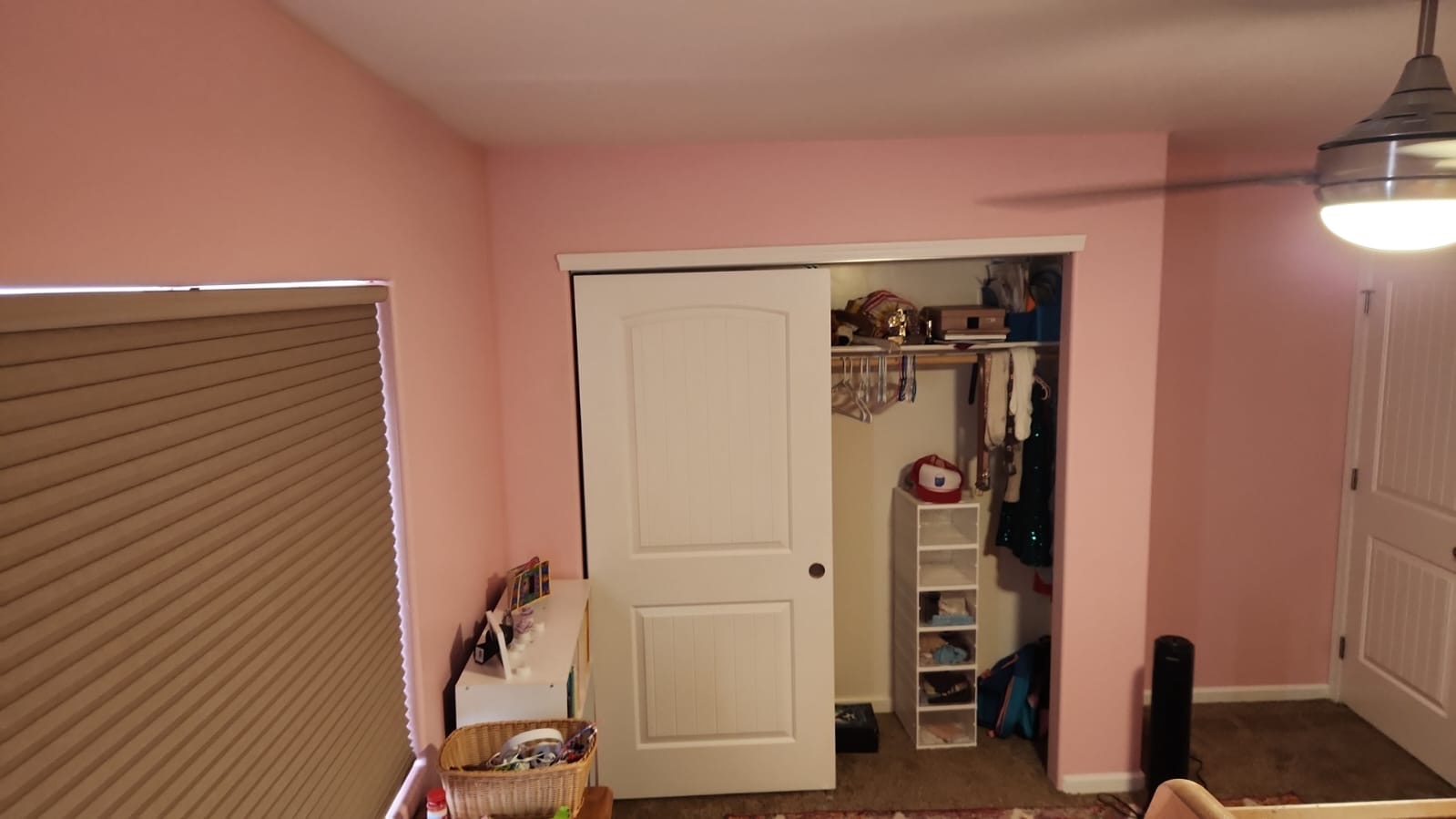 Interior painting in Tucson shown in a soft pink bedroom with white trim, beige blinds, and a ceiling fan, creating a calming and cozy atmosphere.